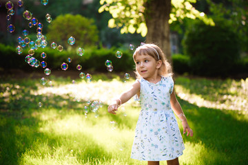 Happy baby girl standing in grass with dandelions