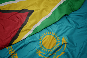 waving colorful flag of kazakhstan and national flag of guyana.