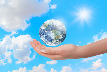 Woman holding diamond globe on her hand with bright blue sky "Elements of this image furnished by NASA"