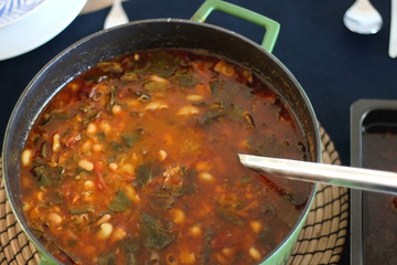 Pot of minestrone soup on a table. Selective focus.