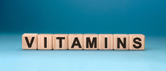 VITAMINS word cube on a blue background. Medical concept.