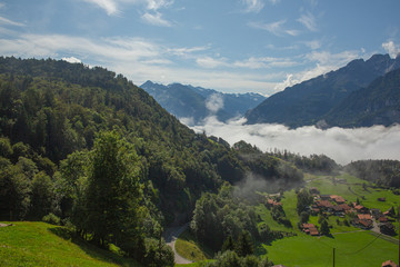 Scenic Alps, slopes basks in sunlight, low clouds lies in valley, Switzerland