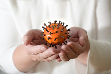 Hands are holding a tangerine with cloves, which looks like a coronavirus, but vitamins strengthen...