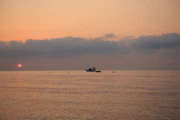 Dawn or sunset at sea. Silhouette of a small boat.