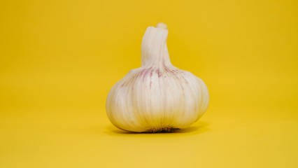 Une gousse d'ail en gros plan sur un arrière plan jaune