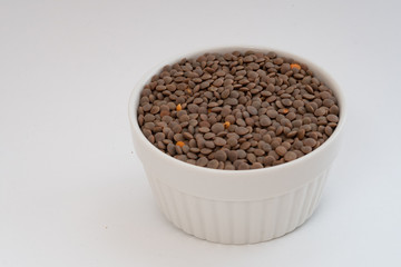View of an isolated white ramekin filled with raw brown lentils