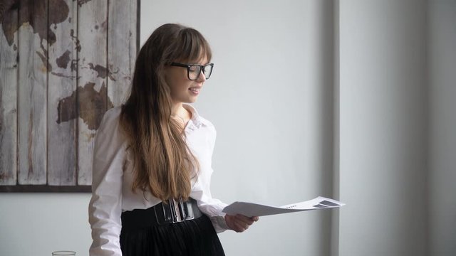 Beautiful business woman talking puts on glasses in modern office