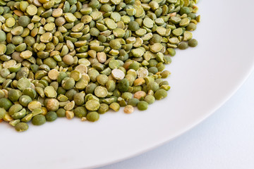 Closeup of raw split peas in a white plate on a white background