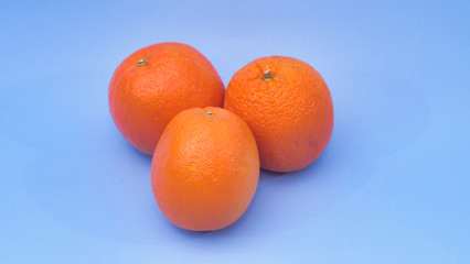 trois oranges sur un fond de couleur bleu