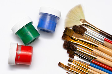 paint brushes and jars of paints on a white background