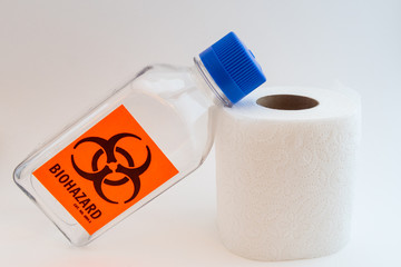 Closeup of a biohazard plastic bottle and a paper toilet roll