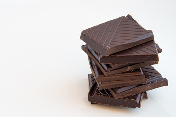 close-up on a pile formed by squares of dark chocolate on a white background