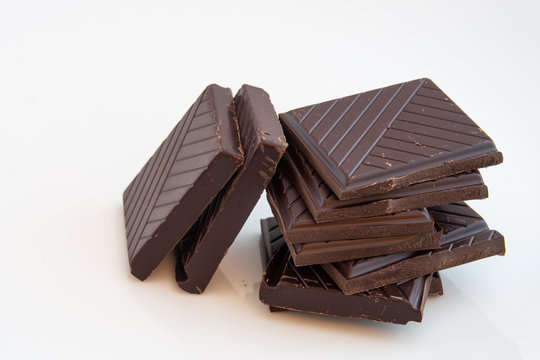 close-up on a pile formed by squares of dark chocolate on a white background
