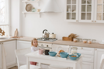 Cute little baby girl with her mom play in a spacious bright minimalistic children's room.