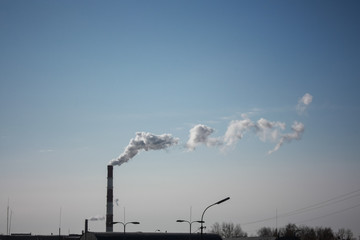 steam smoke coming from a chimney in an industrial zone on the outskirts of a city
