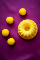bright yellow massage oil and soap in the shape of a flower for the body on a bright purple background
