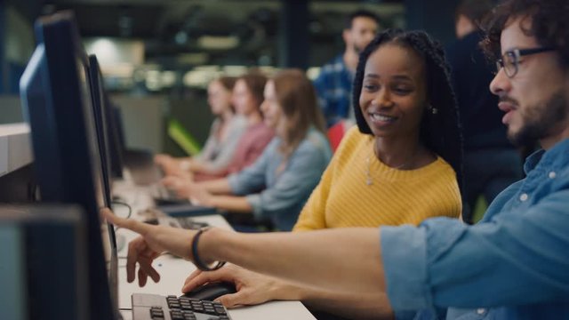 University Library: Bright Black Girl and Smart Hispanic Boy Together Work on Computers, Chat, Discuss Class Assignment and High-Five After Successfully Accomplishing it. Student Exam Study Teamwork