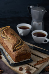 Vegan banana bread with banana on top. loaf cake and coffee. Dark and moody food photography. Selective focus