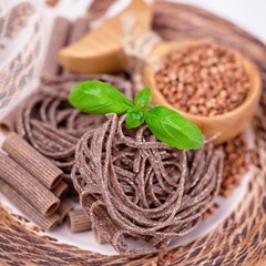Brown raw buckwheat pasta, noodles, buckwheat groats and basil leaves. Gluten free concept