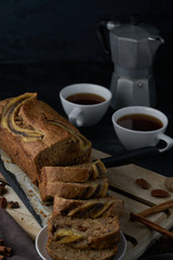 Vegan banana bread with banana on top. loaf cake and coffee. Dark and moody food photography. Selective focus
