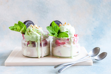  Two Tasty homemade multicolored popsicles ice cream with mint and chocolate cookies leaves in a glass jars