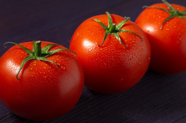 Fresh ripe tomatoes on a purple wooden surface