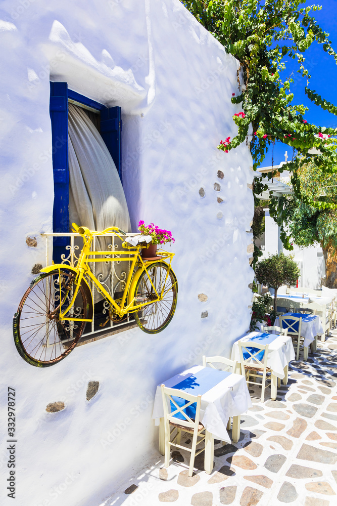 Wall mural Charming Greek taverns on narrow street decorated with old bike and flowers. Naxos island, Cyclades