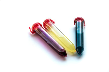 Three test tubes with red, yellow and blue liquid on a white background.