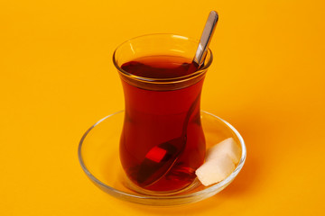 Turkish tea and sugar cube over yellow background