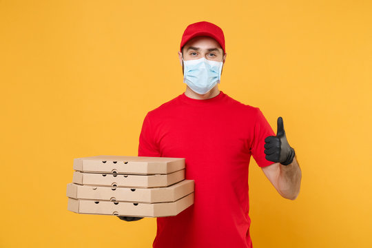 Delivery man employee in red cap blank t-shirt uniform mask gloves give food order pizza boxes isolated on yellow background studio. Service quarantine pandemic coronavirus virus flu 2019-ncov concept