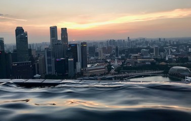 Blond woman in rooftop pool on skyscraper, with skyline in background, Singapore, South East Asia