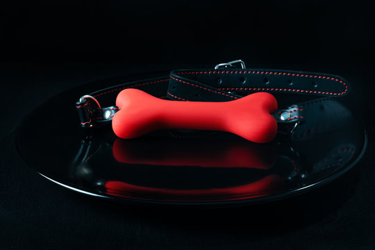 Red Gag Bone Adult Toy On Black Plate