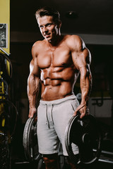 Fototapeta na wymiar Muscular fit man workout and pumping muscles.