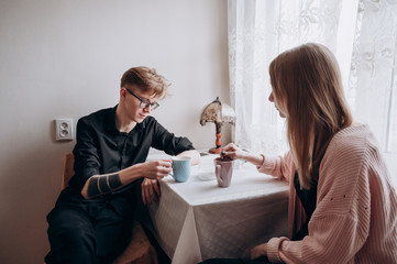 a guy and a girl sit at home in quarantine and drink tea in the kitchen