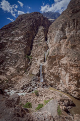 cascades of water flowing from large cracks of rock walls to the river in the canyon of the duck in peru