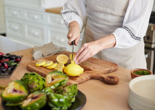 Woman in kitchen slicing lemons for cooking