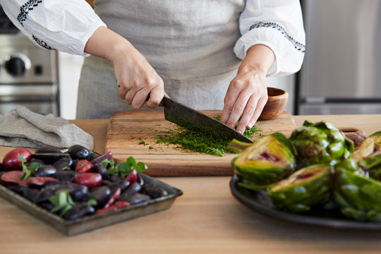 Woman in kitchen cutting herbs for cooking