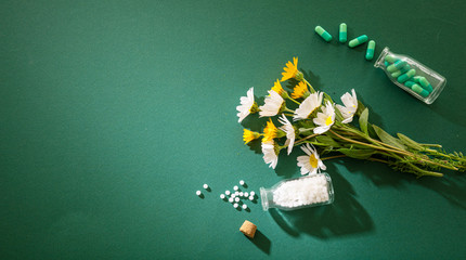 Homeopathy, globules and pills on green background