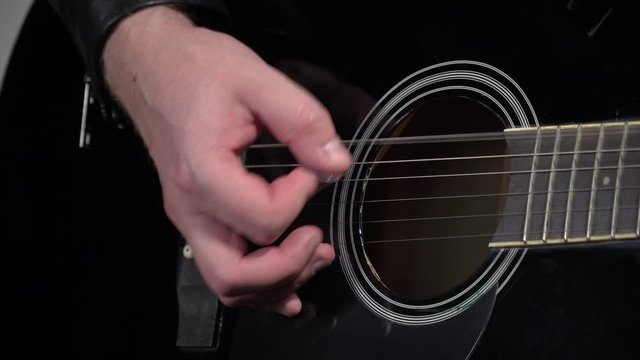 Male hand, crop. Plays on an acoustic guitar, muffled strings.