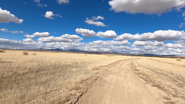 Driving dry arid desert trail driving fast POV. Off road trail riding in 4x4 all terrain vehicle for sport and recreation. Dry arid landscape. Grass lands, rocky terrain and sand dunes. 