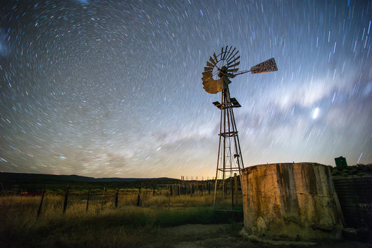 Wide angle image of a windmill / windpomp / windpump on a farm in the karoo with the blazing milkyway overhead