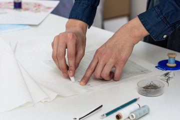 Seamstress is drawing pattern for face mask. Woman prepares to sew protection accessorize from viruses. Healthcare concept