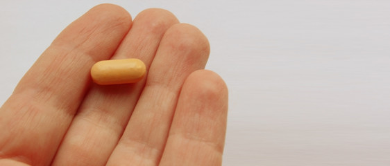 Hand holding the pill in the palm of the hand. Isolated on a white background. Copy space. Flatley