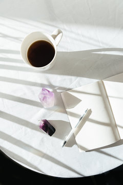 Crystals on table with coffee cup, pen, and notebook