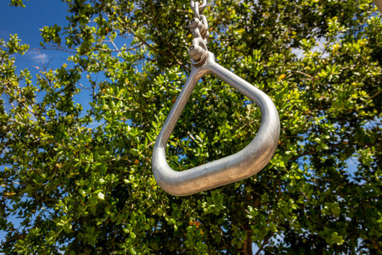 Close up of gymnastics ring at park on sunny day with green tree in bacground