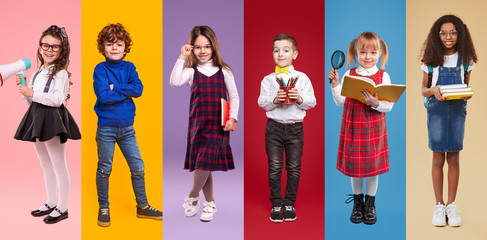 Obraz premium Multiethnic little schoolgirls and schoolboys against colorful background