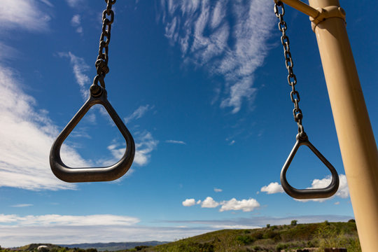 Gymnastics rings at park on sunny day with blue sky