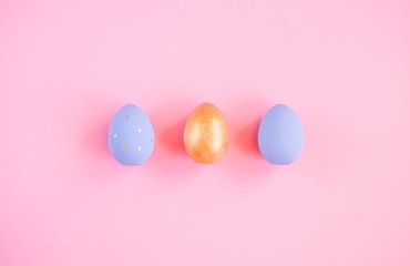Gold and blue easter eggs on pink background.