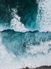 Aerial drone view of spashing waves in blue ocean