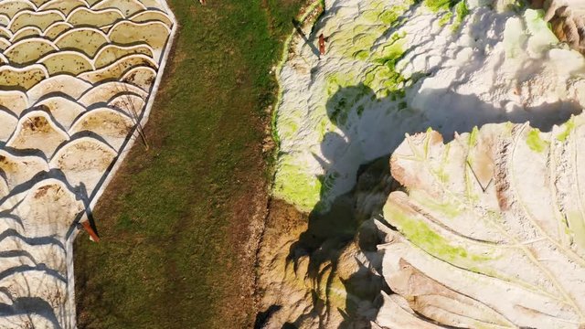 Elevated view photograph of geothermal activity produced thermal spring waters in Egerszalok, Hungary, that sit within colorful textured, terraced limestone formations lined with travertine
